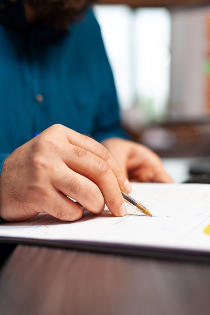 Property Managers closeup of businessman hand sitting at desk analyzing document with data chart